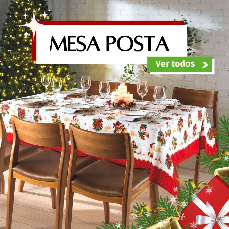 Imagem promocional mostrando uma mesa decorada para a ceia: toalha natalina estampada, taças, pratos e velas ao centro, com uma árvore iluminada ao fundo. O banner superior traz o texto “Mesa Posta” e um botão verde “Ver todos”, convidando a conhecer a linha completa.
