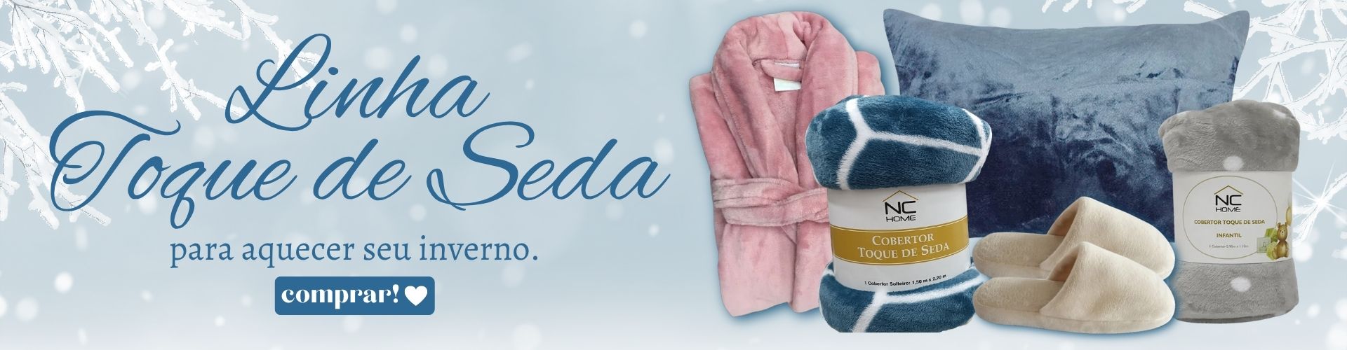 A imagem é um banner promocional com o tema de inverno. O fundo apresenta elementos de neve e flocos congelados, transmitindo uma sensação de frio. Em destaque está a frase "Linha Toque de Seda – para aquecer seu inverno". Abaixo, são exibidos produtos da linha: um roupão rosa, um cobertor azul com branco, uma almofada azul aveludada, uma manta cinza, um par de pantufas bege e outro item enrolado da mesma linha. Há também um botão com a palavra “comprar!” em destaque. A imagem promove itens aconchegantes e macios ideais para os dias frios.